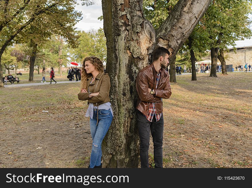 Man And Woman Wearing Leather Jackets Standing Under Tree