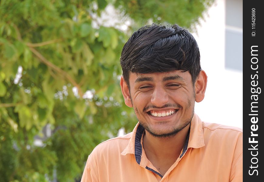 Man Smiles While Taking Photo Near Tall Tree at Daytime