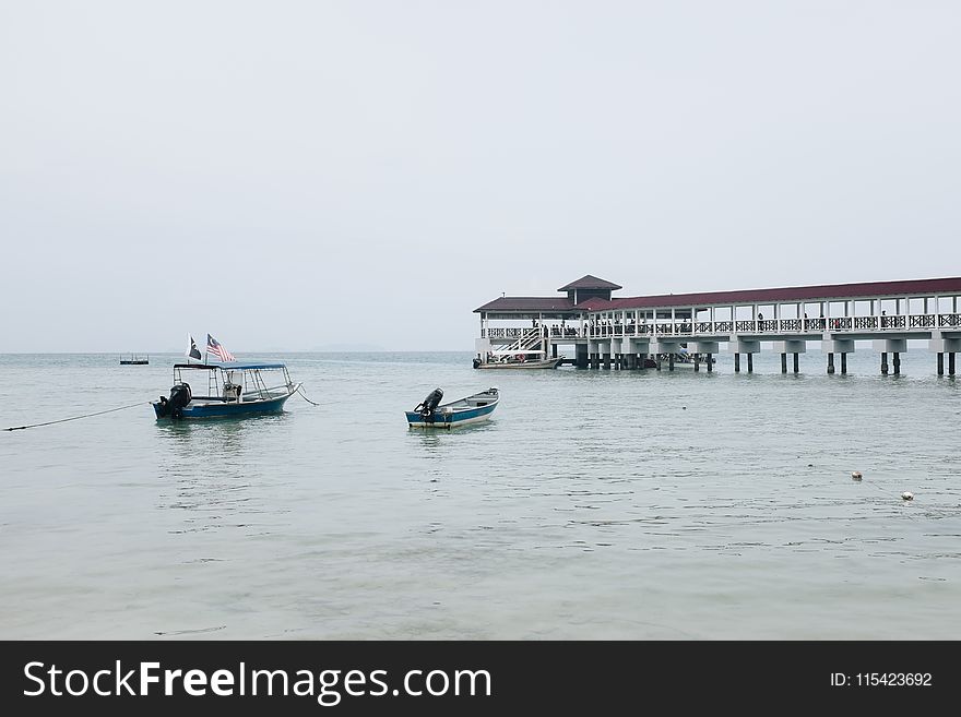 White And Blue Boat On Body Of Water Near Pier