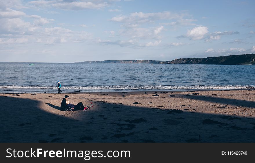 Person Walking Near Ocean Under White Sky