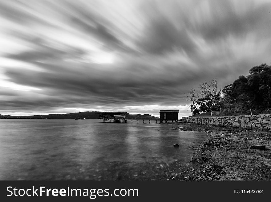 Time Lapse Photo of a House Near Body of Water in Grayscale