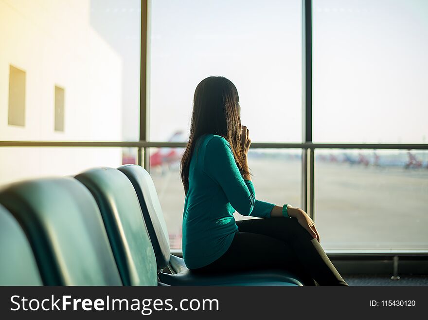 Asian woman passenger using smartphone and checking flight or online check in and travel planner at international airport