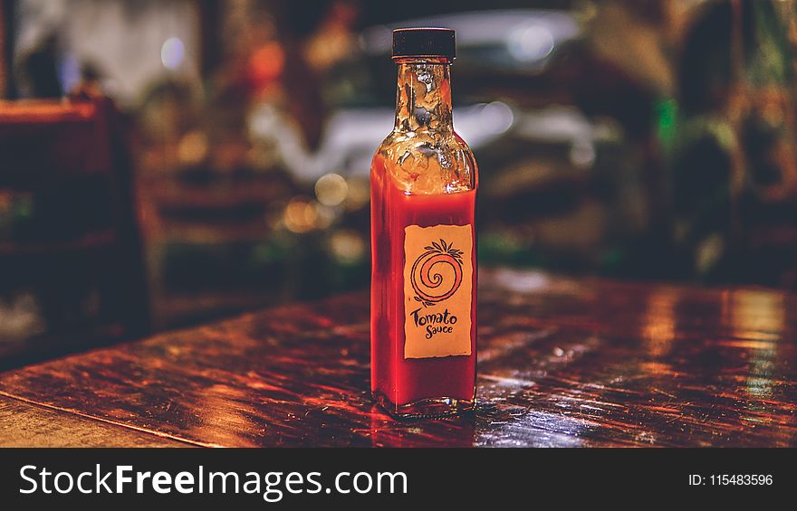 Selective Focus Photo of Tomato Sauce Bottle on Top of Brown Table