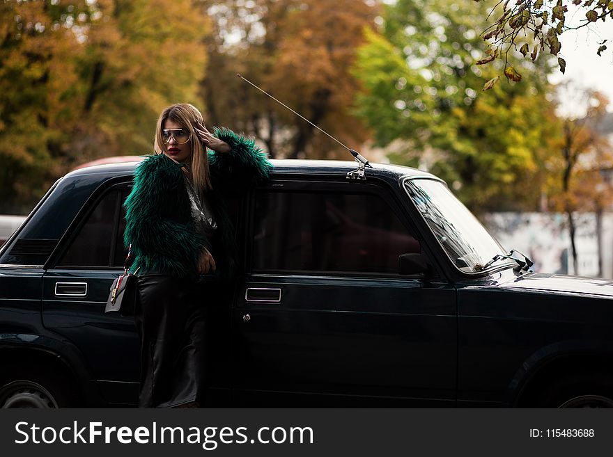 Woman Leaning On Car Surrounded Trees