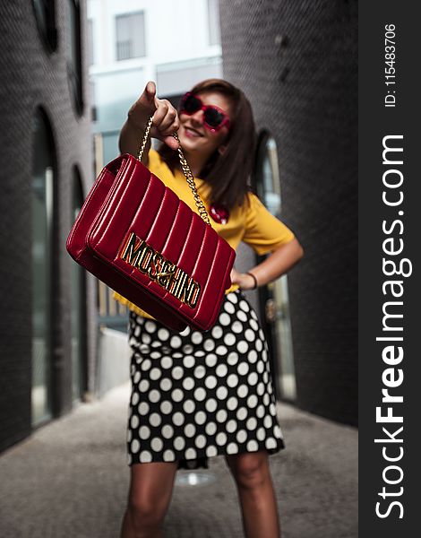 Woman Wearing Yellow Crew-neck T-shirt While Holding Red Handbag