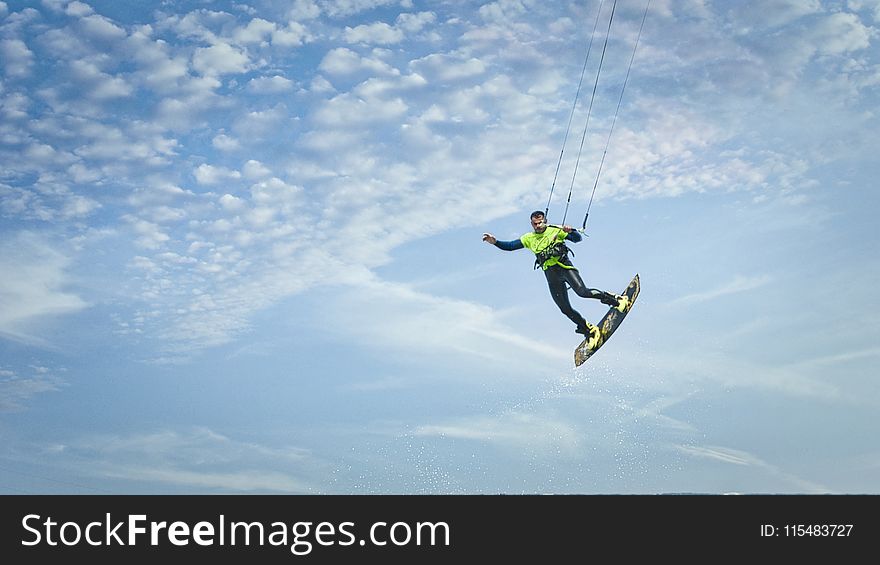 Man Wearing Green And Black Wetsuit Riding Wakeboard