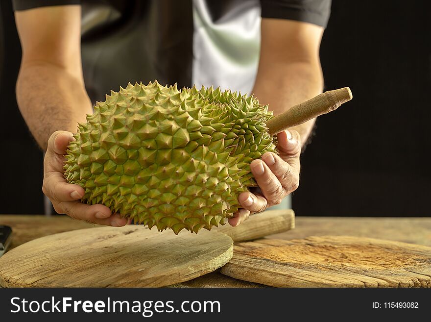 Guys are cutting Durain the King of fruits on wooden background