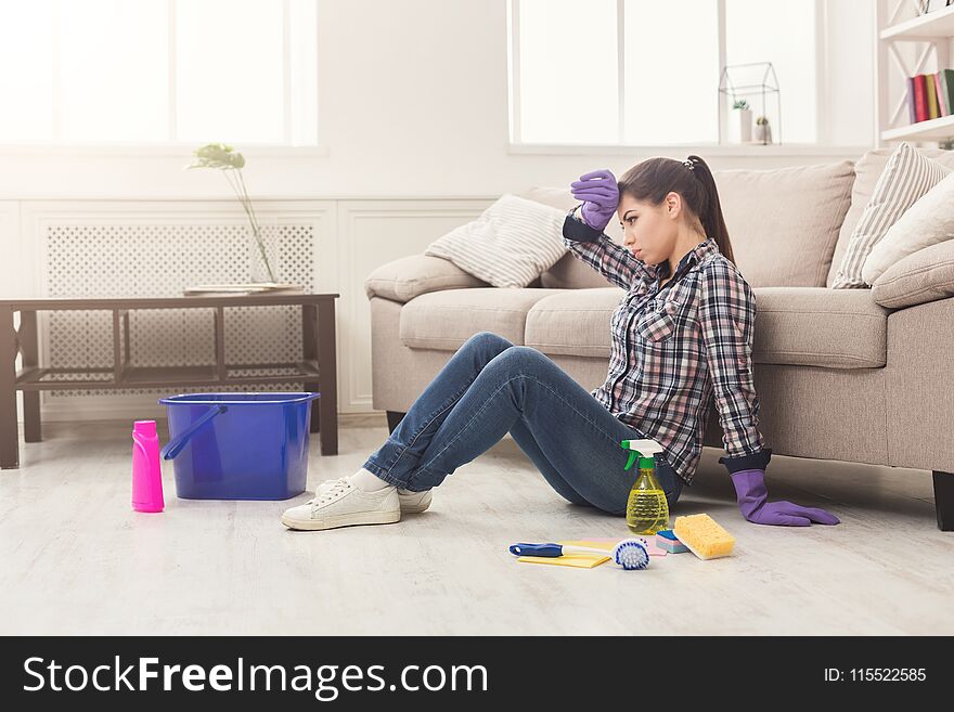 Tired Woman Cleaning Floor With Lots Of Tools