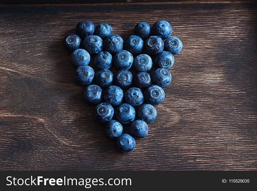 Ripe blueberry heart wooden brown background selective focus. Ripe blueberry heart wooden brown background selective focus.