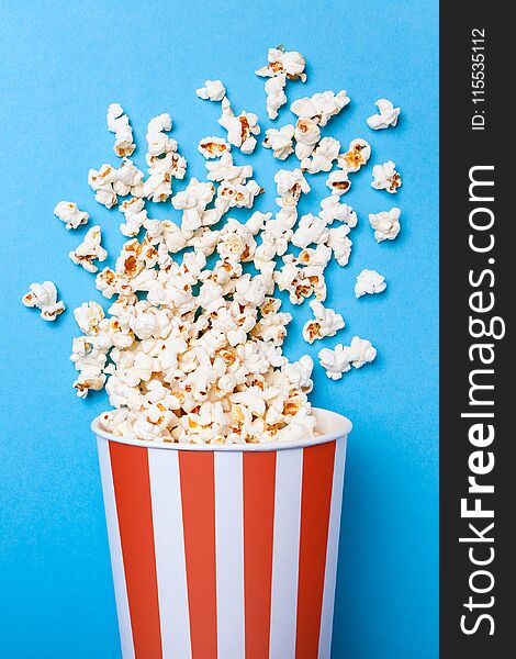 Spilled Popcorn And Paper Bucket In Red Strip On Blue Background. Copy Space For Text