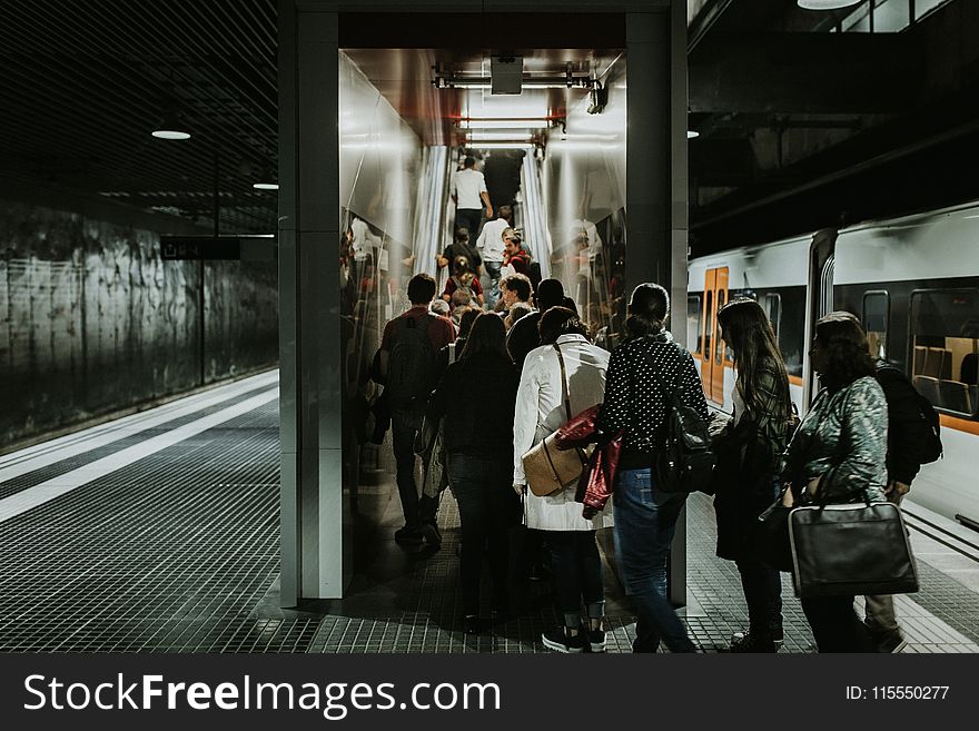 Grayscale Photography Of People Falling In Line At Train Station