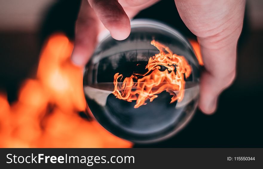 Person Holding Clear Glass Ball With Flame