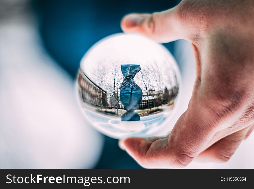 Person Holding Sphere Reflecting Dna-shaped Statue