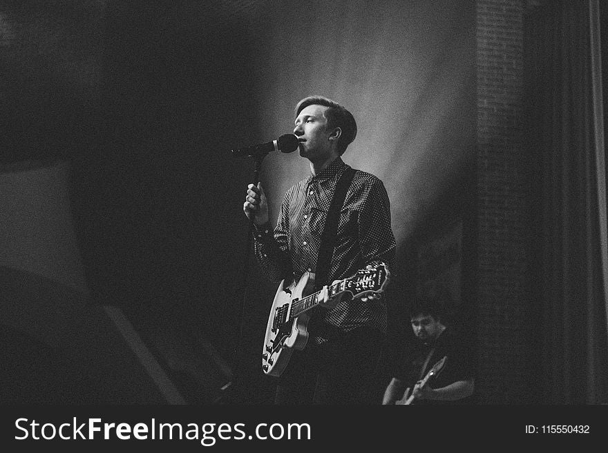 Grayscale Photography Of Person Near On Pedestal Microphone