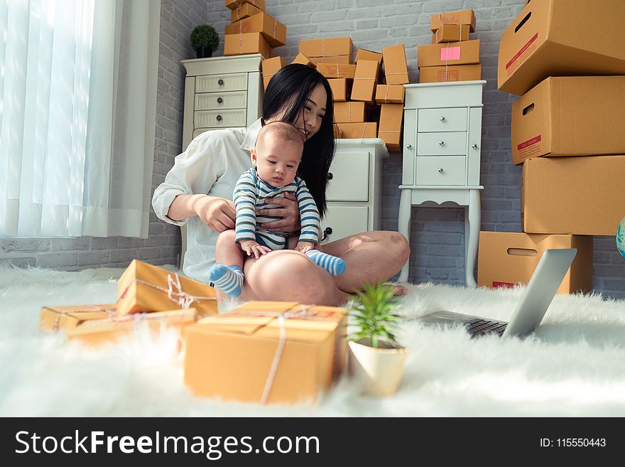 Woman Sitting On Floor While Holding Baby
