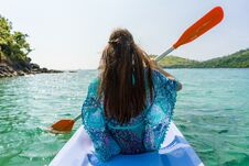 Young Woman Paddling A Canoe Along The Shore Of An Idyllic Island Royalty Free Stock Photography