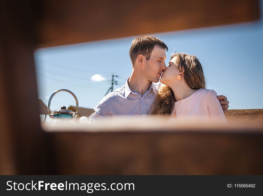 Young couple resting outdoors, handsome men and cute women kissing on wooden terrace, happy family concept. Young couple resting outdoors, handsome men and cute women kissing on wooden terrace, happy family concept