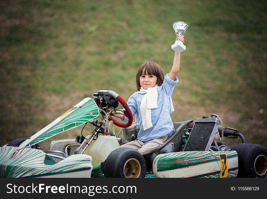 Cute child, riding go cart, wins champion cup, happiness winner concept