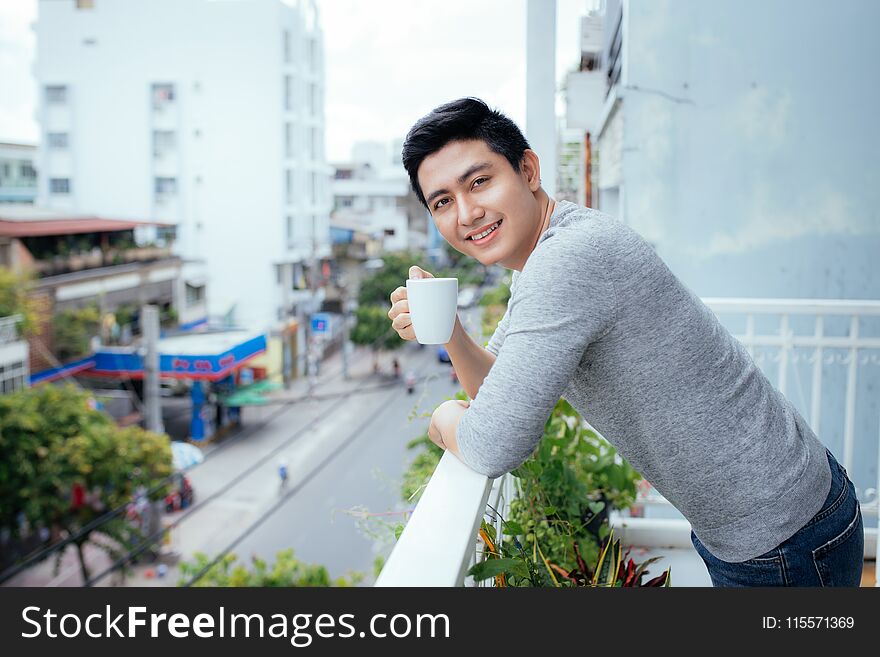 Handsome Guy Relaxing On A Balcony, On A City Backgroun