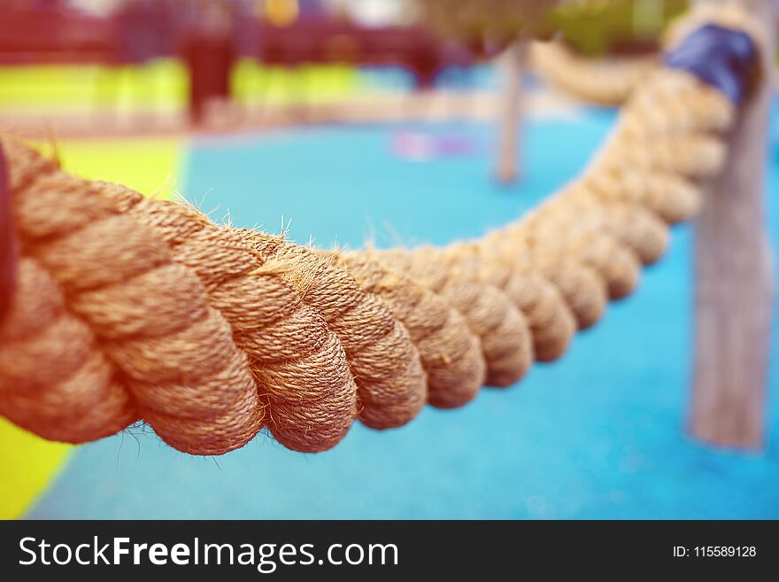 Thick braided rope on the Playground for children. Tied to poles. Photographed along. The background is blurred.