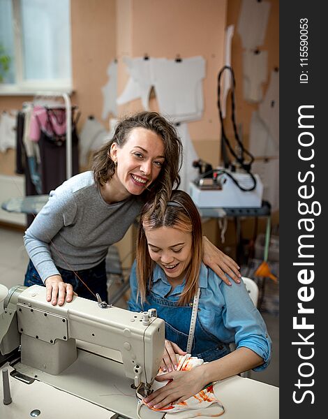 Two women, dressmakers, work and laugh in the workshop. Two women, dressmakers, work and laugh in the workshop