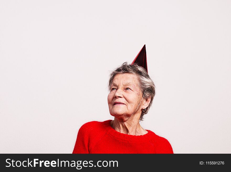 Portrait of a senior woman in studio on a gray background. Party concept. Copy space.