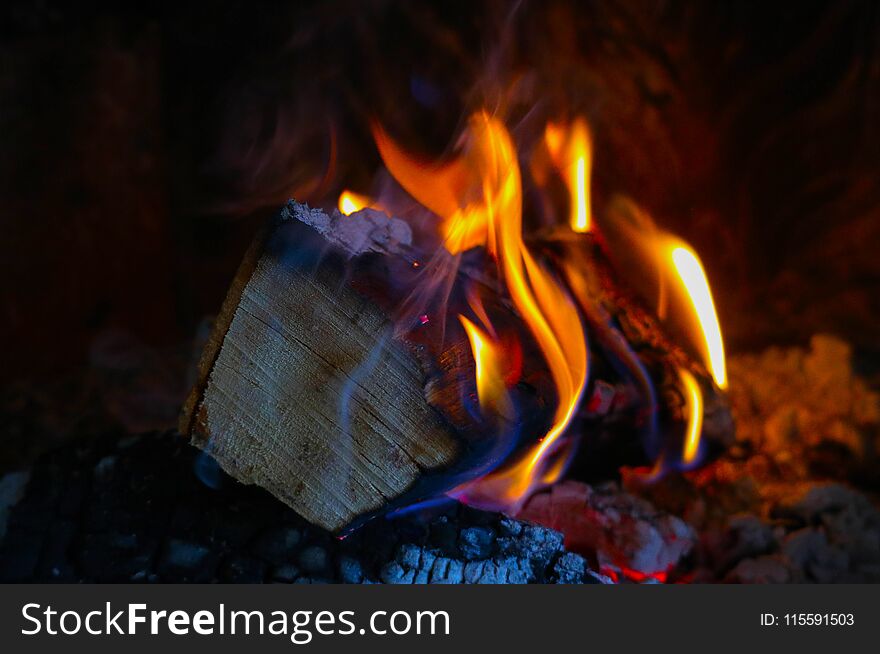 Bright colorful flame, burning wood at the fireplace. Firewood brick at the fire, closeup.