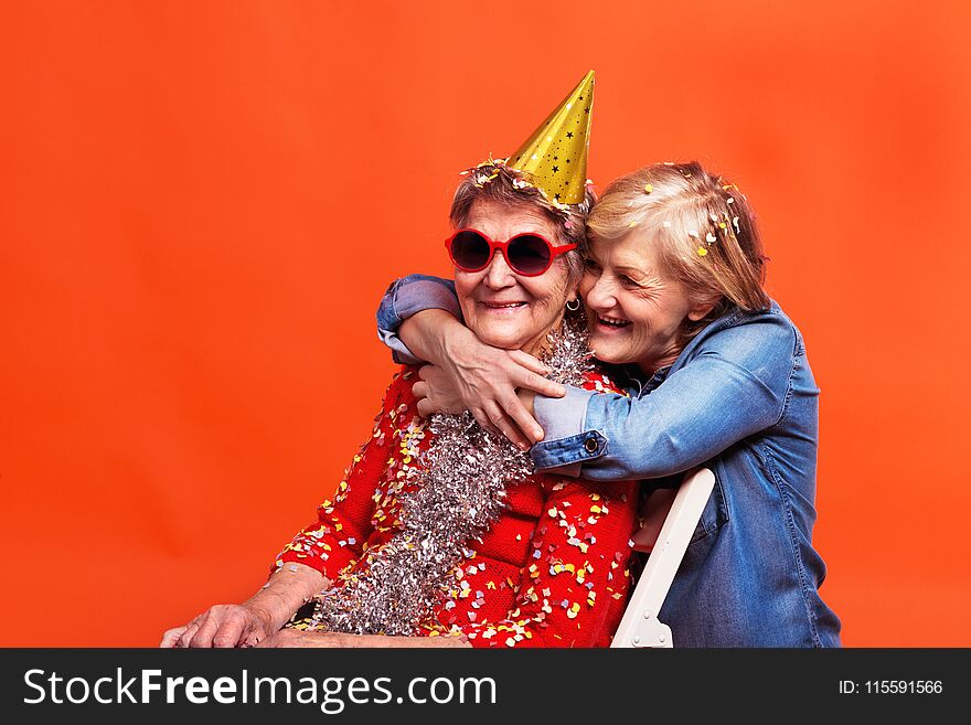 Portrait of a senior women in studio on a red background. Party concept. Close up.