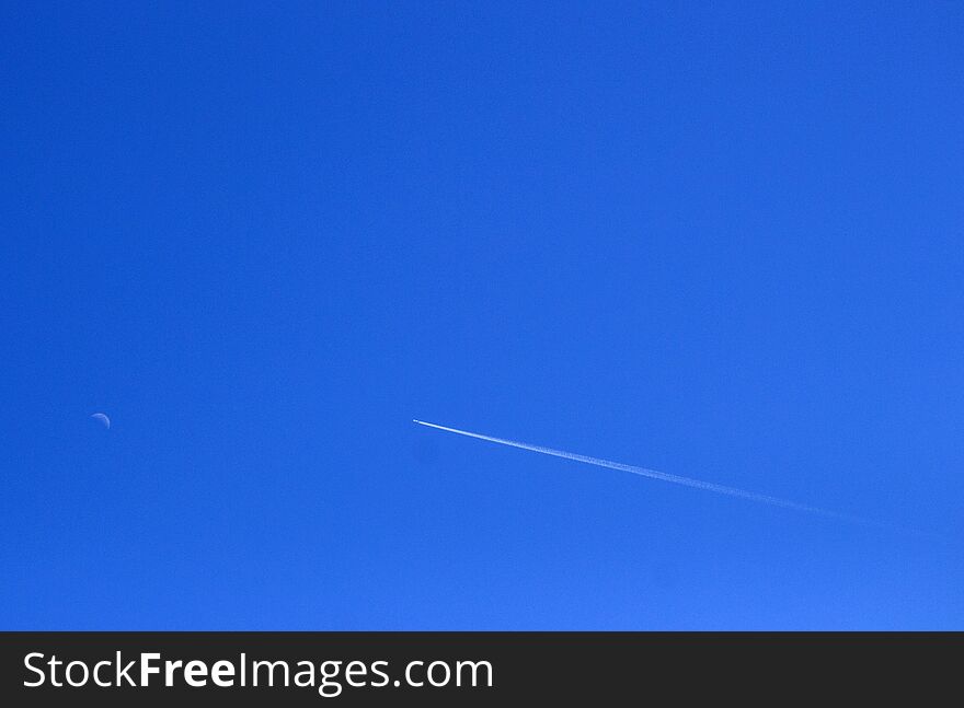 Airplane crossing the sky.rnThe moon present in the sky during the day