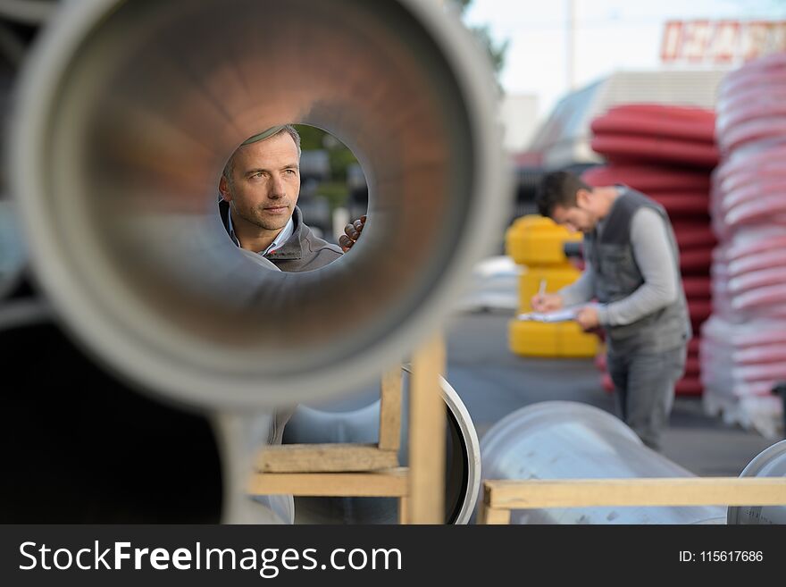 Male supervisor examining large pipe at construction site man