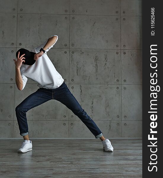 Teenager guy in baseball cap and sneakers, jeans and white sweater dancing hip-hop. Dynamics of modern dance movement. Youth fashion. Man is unrecognizable. Teenager guy in baseball cap and sneakers, jeans and white sweater dancing hip-hop. Dynamics of modern dance movement. Youth fashion. Man is unrecognizable