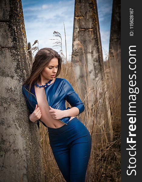 Woman Wearing Blue Leather Jacket Leaning On Concrete Post