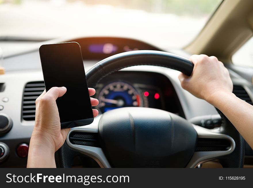 Person Holding Black Smartphone and Vehicle Steering Wheel