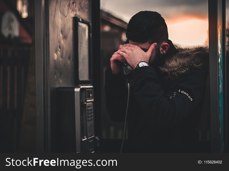 Man Wearing Black Parka Jacket Holding Telephone