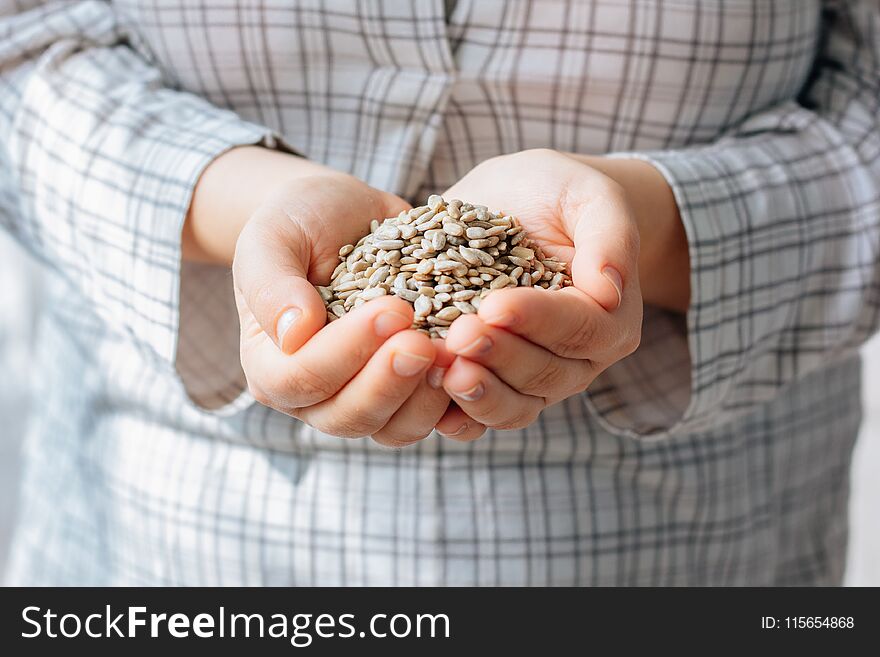 Woman hands holding sunflower seeds without shell.