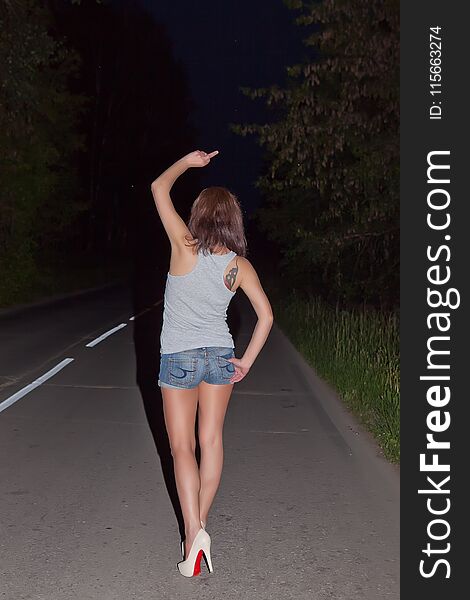 Girl showing obscene gestures at walking distance along road