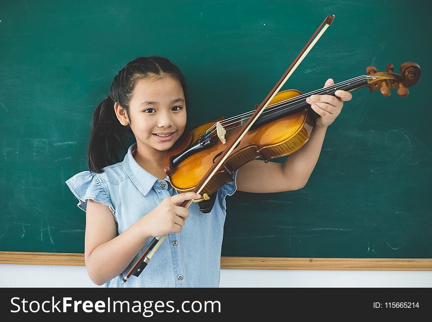 A littel cute girl playing violin on music class room at school. A littel cute girl playing violin on music class room at school