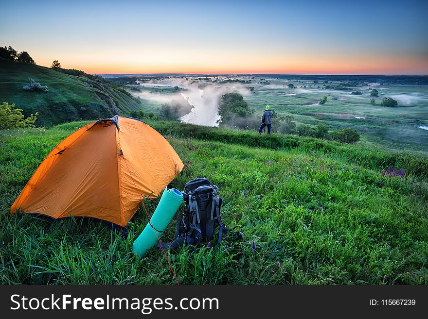 Orange Tent And Backpack On Hill With Tourist