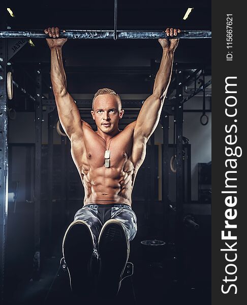 Shirtless muscular man in military pants doing exercises on horizontal bar. Shirtless muscular man in military pants doing exercises on horizontal bar.