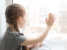 Lonely Little Girl Near Window Indoors Stock Photo