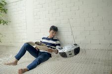 Free Boy Sitting Near Radio Holding White Catalog Royalty Free Stock Images - 115693919