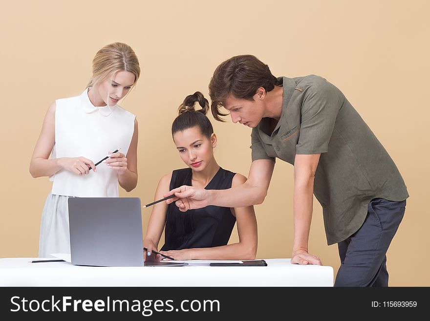 Two Woman and One Man Looking at the Laptop