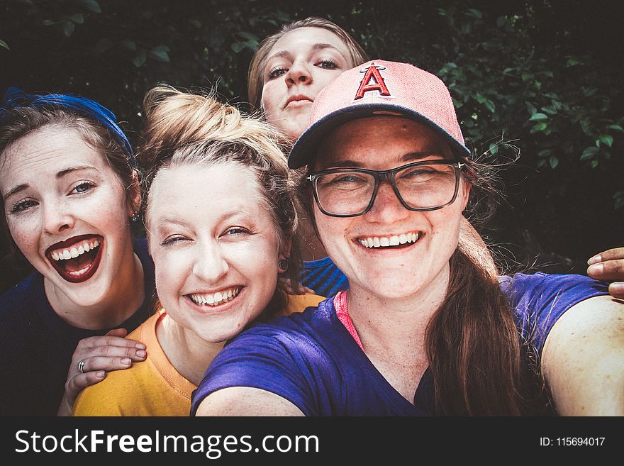 Four Women In Front Of Green Bushes