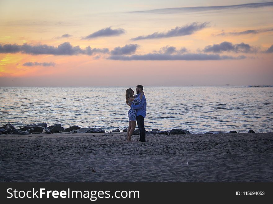 Couple Face to Face Stands on Seashore Near Calm Water during Golden Hour