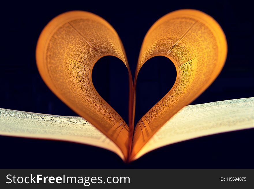 Two Lighted Pages of Book Formed Into Heart Shape Inside a Dark Room