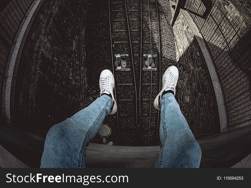 Person in Blue Denim Stonewashed Fitted Jeans and White Low-top Sneakers