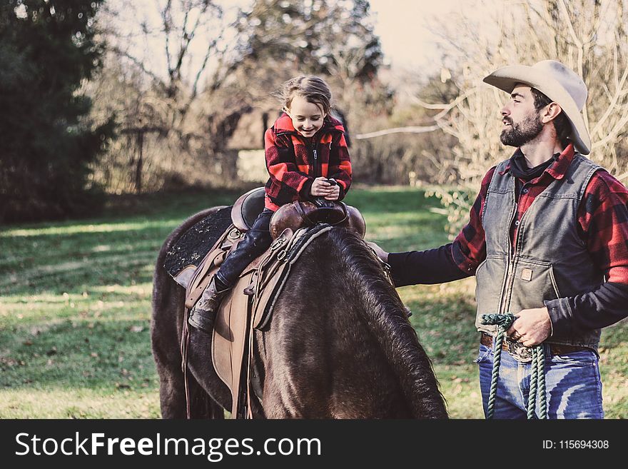 Little Girl Riding Horse Beside Man