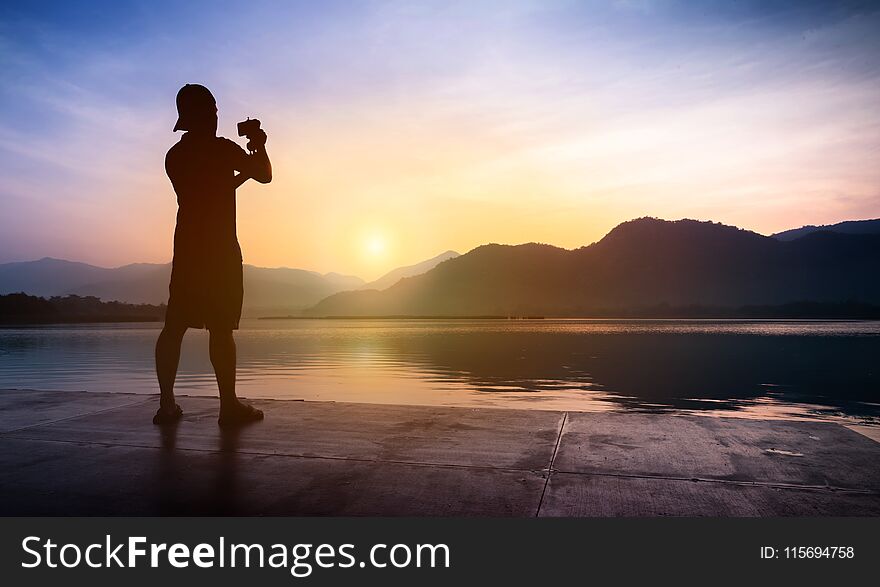 Man traveler taking photos of sunset at mountain and river lands