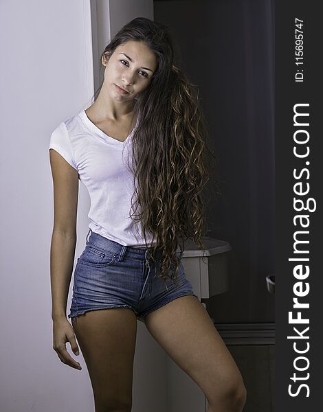 Young girl at home wearing a white t-shirt and blue shorts. Young girl at home wearing a white t-shirt and blue shorts