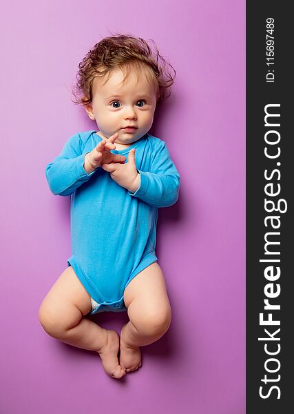 Little infant baby with hair lying down on purple background